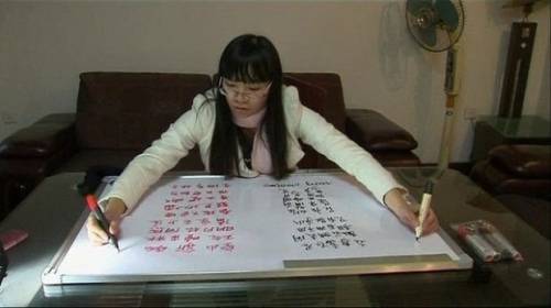 Китайская девушка пишет одновременно обеими руками
